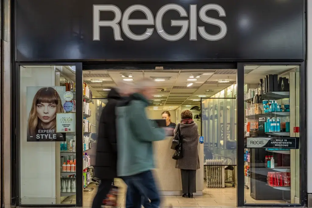 A busy storefront of a Regis salon, featuring hair care products and clients being assisted inside.