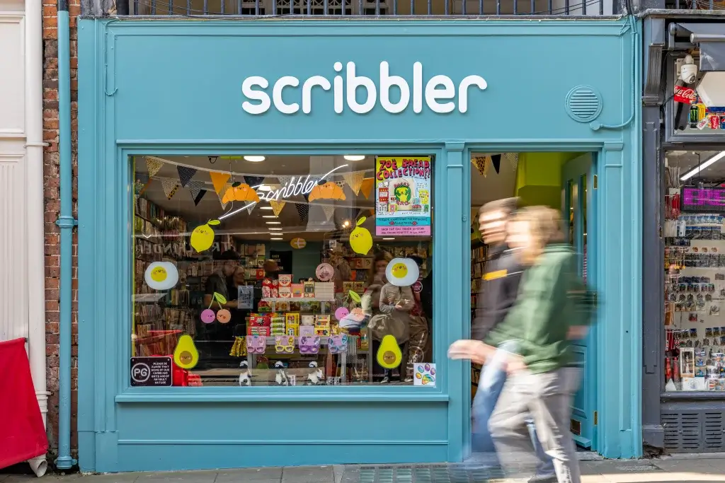 A vibrant shopfront of “Scribbler” with colorful decorations, showcasing gifts and cards through the window.