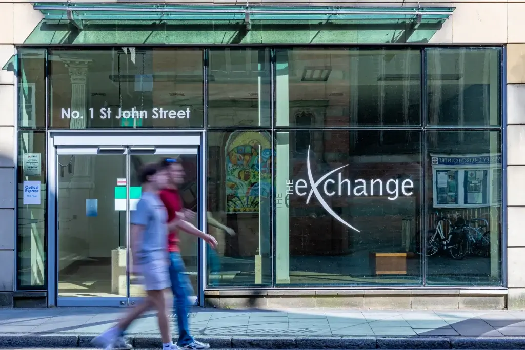 Glass entrance of No. 1 St John Street, with people walking by and signage for Optical Express visible on the left.