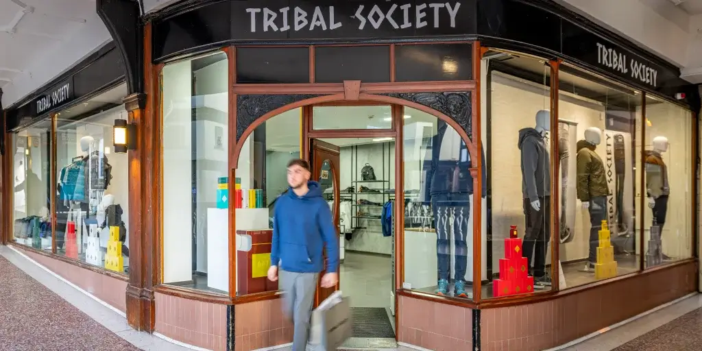 A storefront labeled "Tribal Society" features stylish clothing displays and colorful boxes outside, creating an inviting shopping atmosphere.