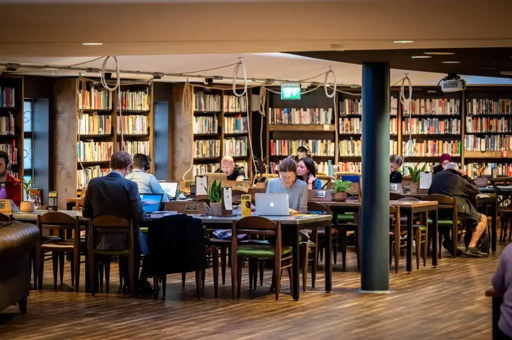 People studying, sitting at tables with laptops in Storyhouse Chester