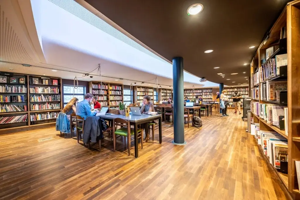People studying, sitting at tables with laptops in Storyhouse Chester