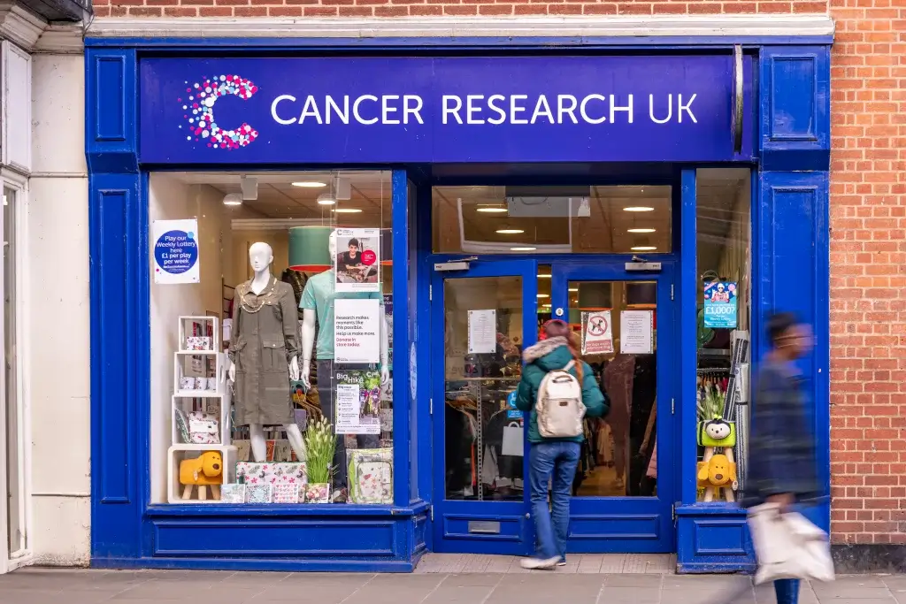 a young woman walks into a blue front shop with a mannequin to the side and posters fill the window