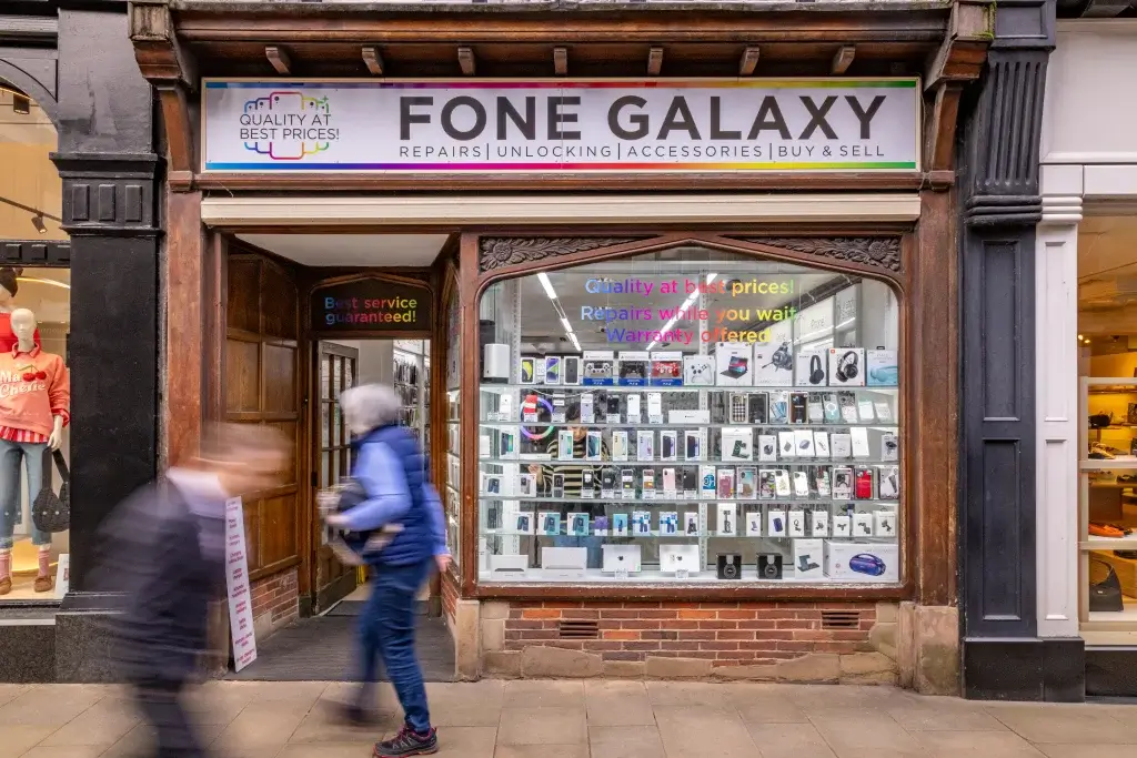 A storefront named "Fone Galaxy" displays various mobile devices and accessories, with signs promoting quality repairs and services.