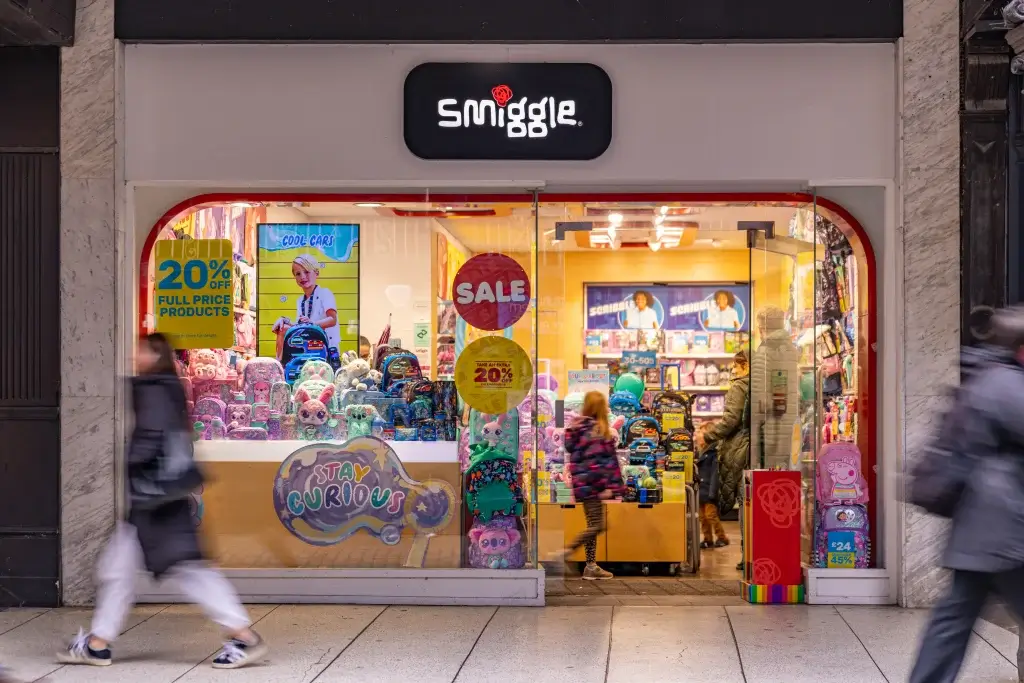 A brightly lit Smiggle store showcasing colorful backpacks, toys, and promotional signage highlighting sales and discounts.