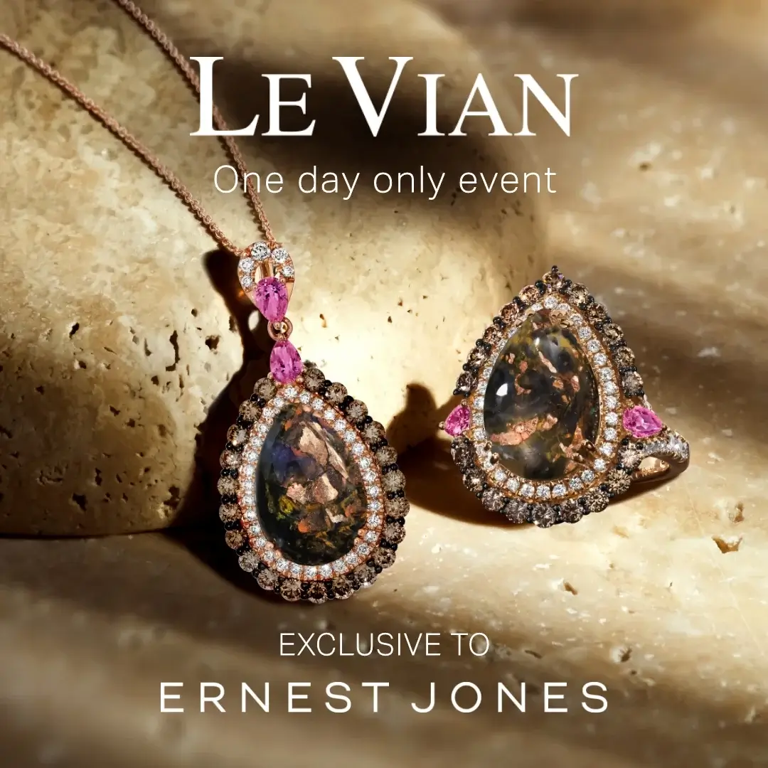 A luxurious pink gemstone necklace and matching ring set on a textured stone surface, featuring intricate designs and sparkling diamonds.