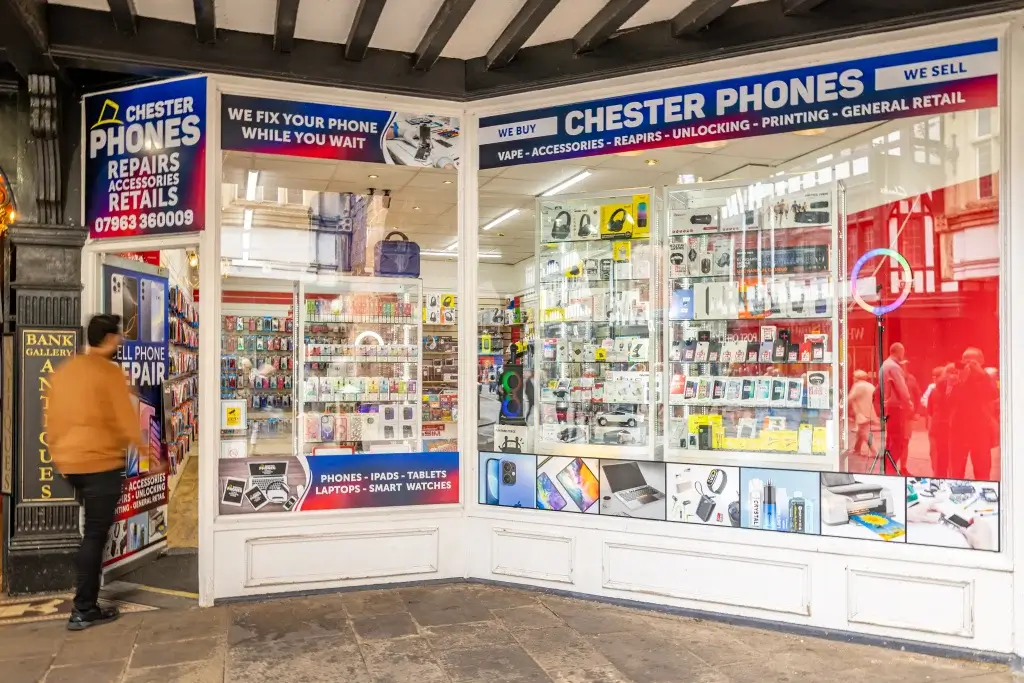 Exterior view of Chester Phones shop, showcasing mobile accessories, repairs, and various tech items in vibrant window displays.