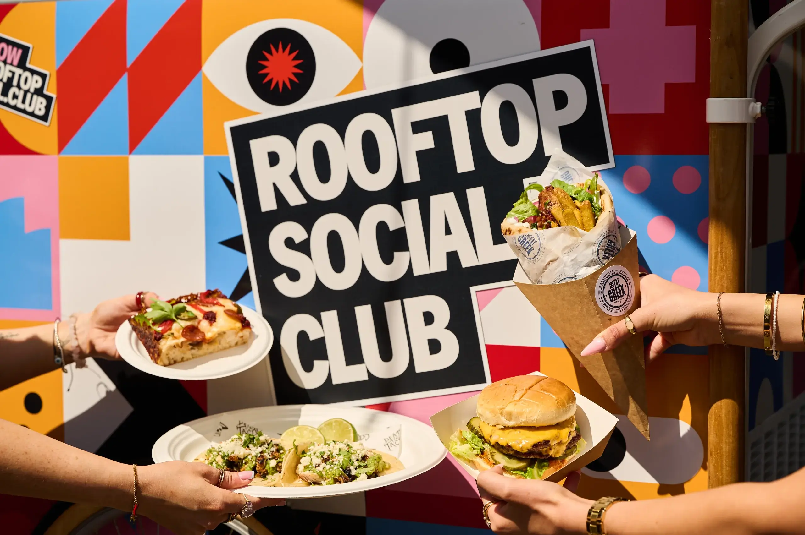 A colorful food display featuring pizza, tacos, and a burger, set against a vibrant "Rooftop Social Club" backdrop.