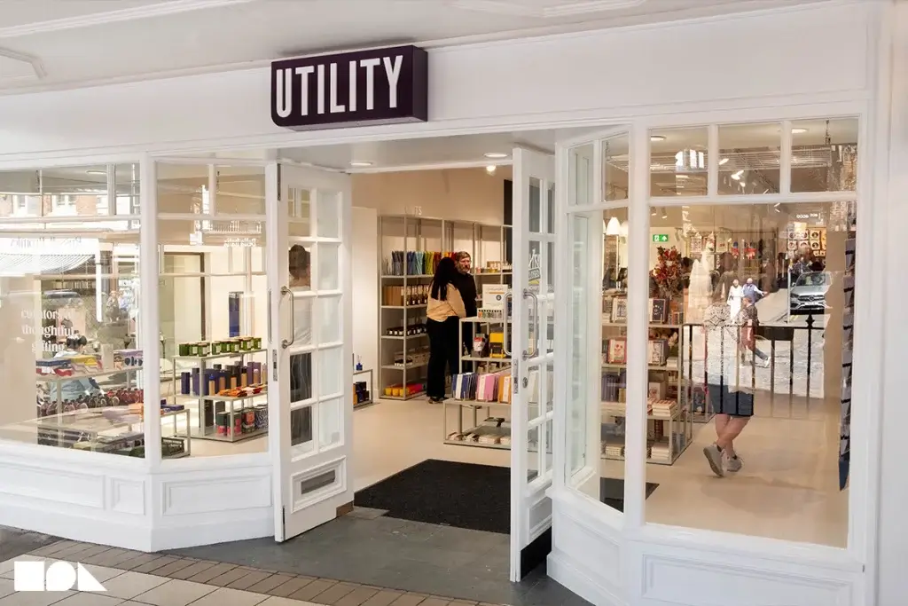 The entrance of Utility store features large glass doors displaying various gift items and customers browsing inside.