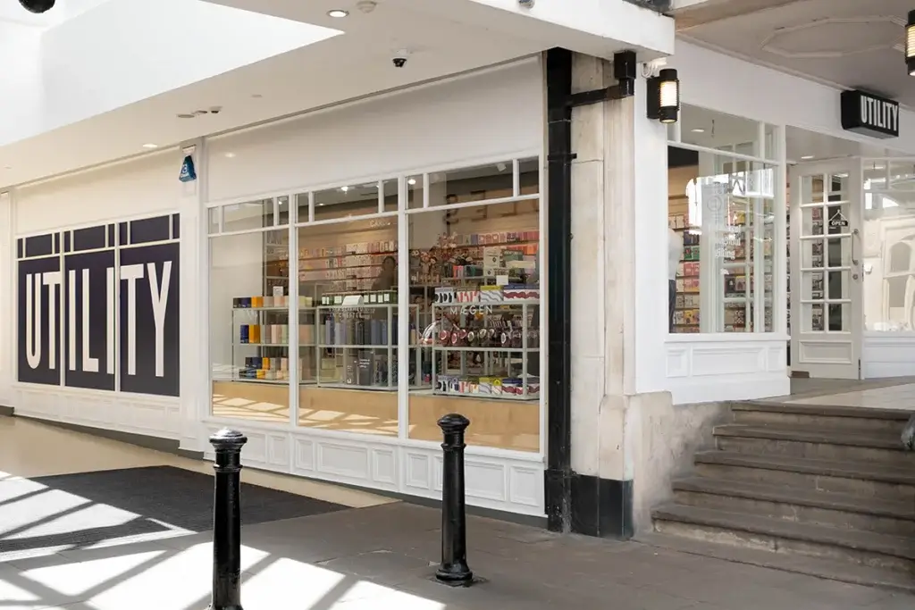 Exterior view of the "Utility" store showcasing colorful products through large glass windows in a well-lit shopping area.