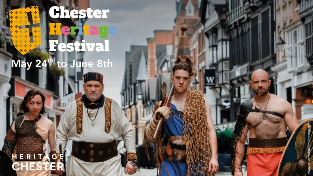 Four historical figures in traditional costumes walk down a charming, cobblestone street during the Chester Heritage Festival.