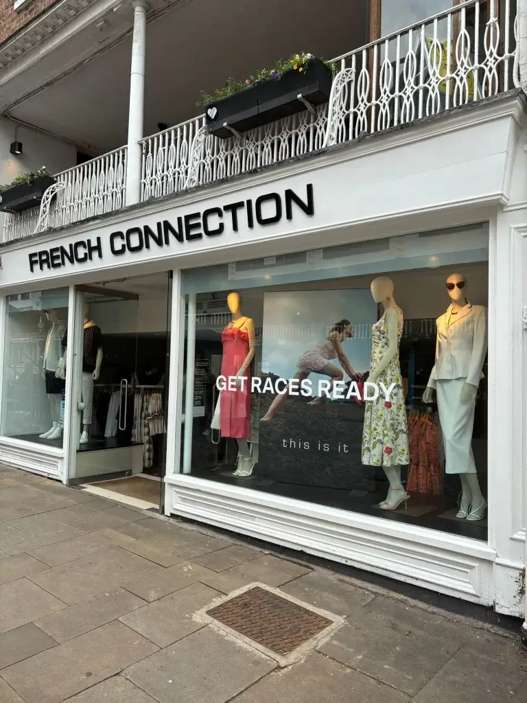Storefront of French Connection featuring mannequins in summer dresses and a promotional sign reading "GET RACES READY."