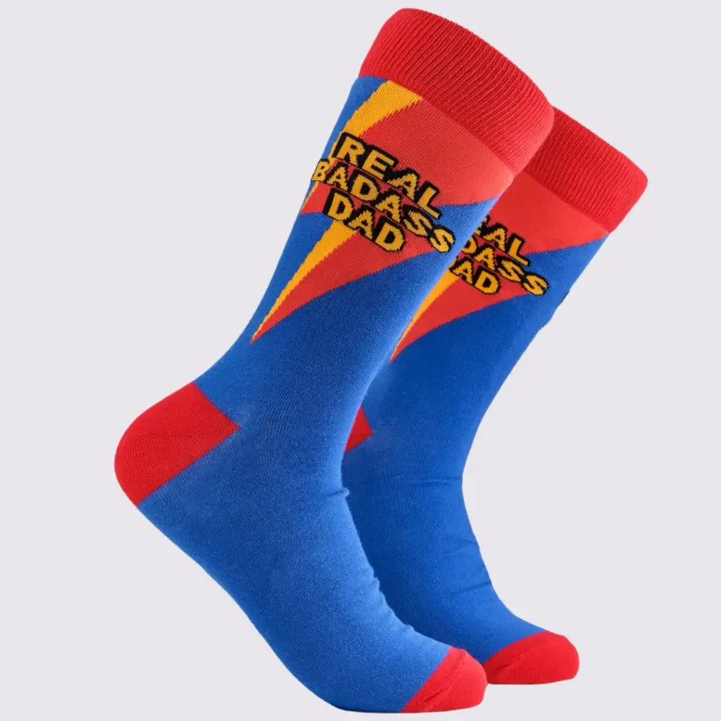 Colorful socks displaying the text "REAL BADASS DAD" in bold, with a lightning bolt design, featuring blue and red colors.