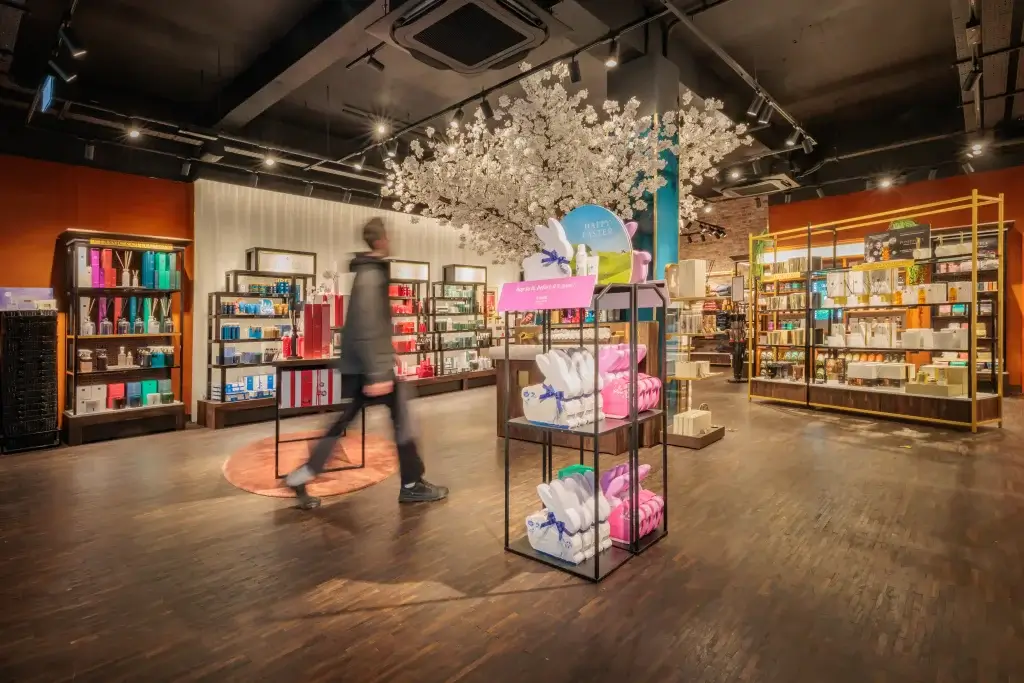 Store interior with Easter display of bunny-shaped boxes under a faux blossom tree and a blurred shopper.