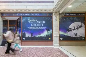 A festive storefront features "Santa's Enchanted Grotto" advertisement in Chester, with people walking past under a starry backdrop.