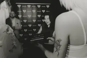 Woman smiling as she accepts a framed award in front of a CSA25 heart-branded backdrop, two attendees partly visible.