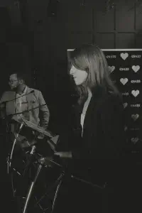 Woman in blazer at a podium in profile, holding a small triangular award, backdrop with CSA25 heart logos.