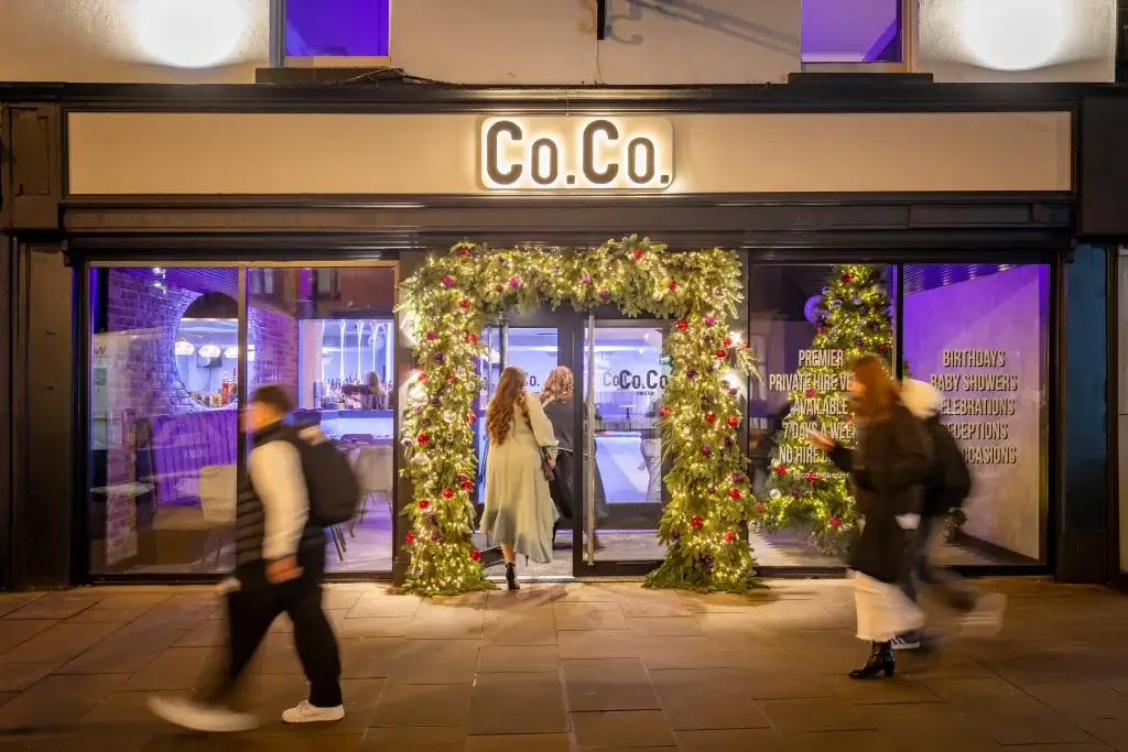 Festively decorated entrance of Co.Co. in Chester, with holiday lights and wreaths; guests entering the venue.
