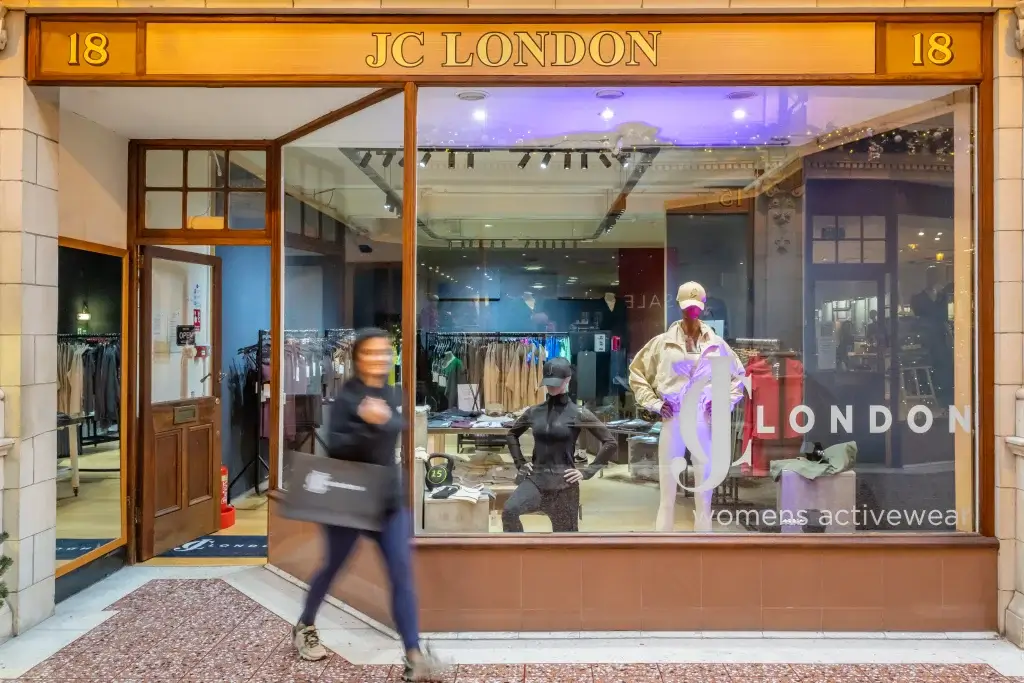 A storefront display for JC London featuring stylish activewear mannequins and an array of colorful athletic clothing and accessories.