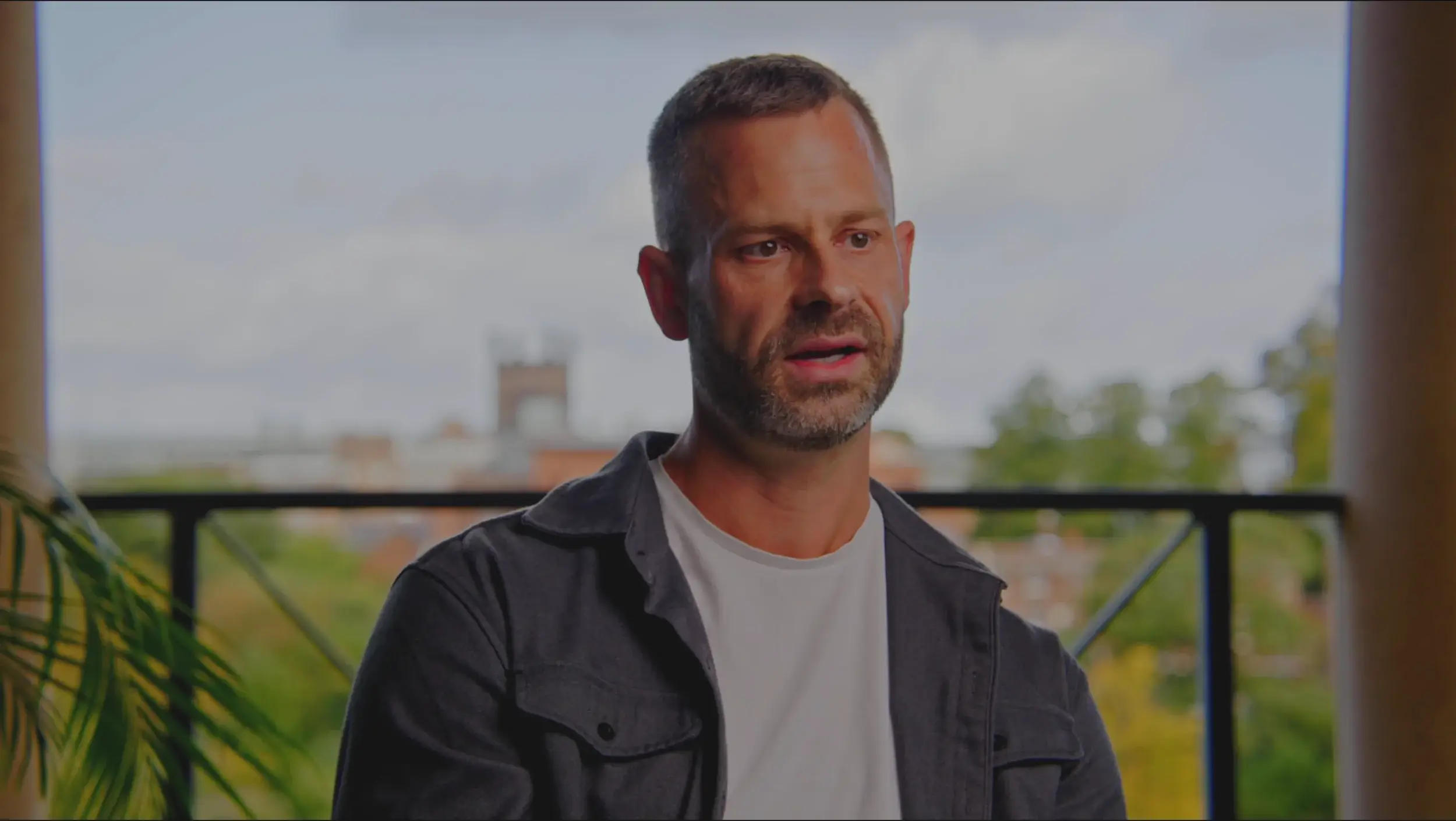 A Man speaking to camera with a backdrop of Chester Cathedral and trees