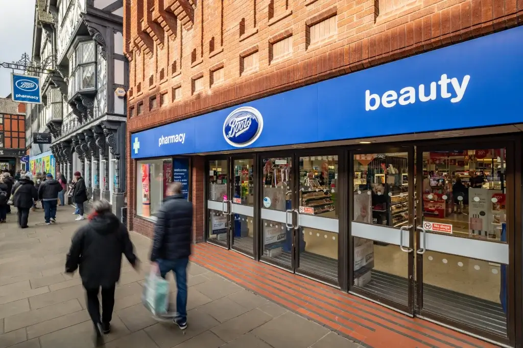 Boots pharmacy and beauty shopfront with blue signage and glass doors set in a red-brick façade on a busy pedestrian street