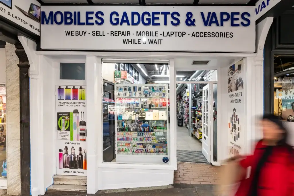 Mobiles Gadgets & Vapes shopfront with white façade and large blue sign, window displays of phones, accessories and vape kits.