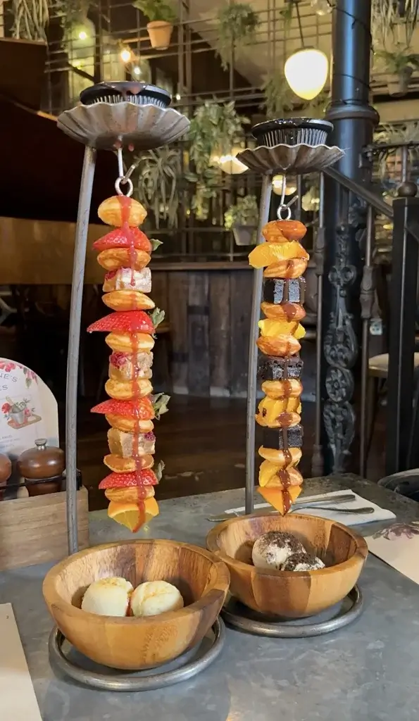 two hanging pancakes on kebab sticks with fresh fruit and chocolate and ice cream