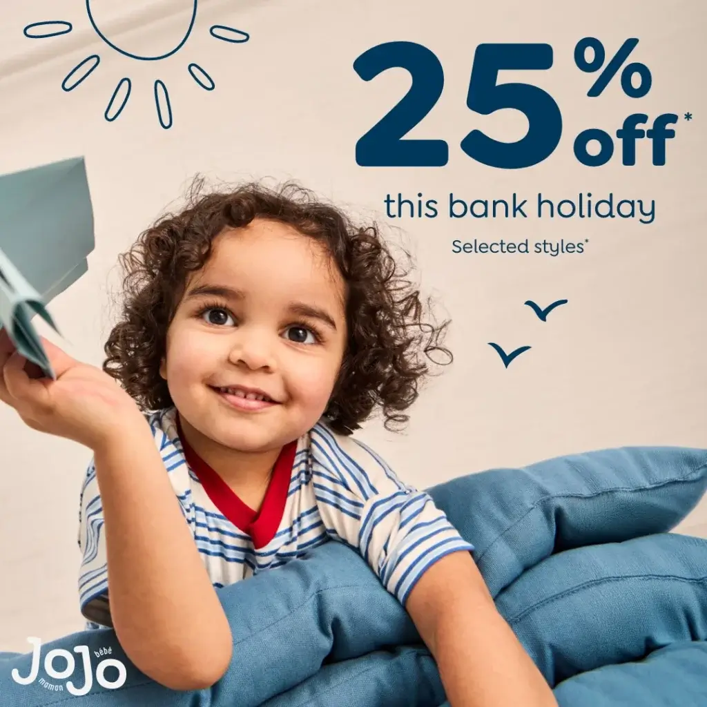 Smiling toddler with curly hair holding a paper plane, leaning on blue cushions with "25% off this bank holiday" text above.